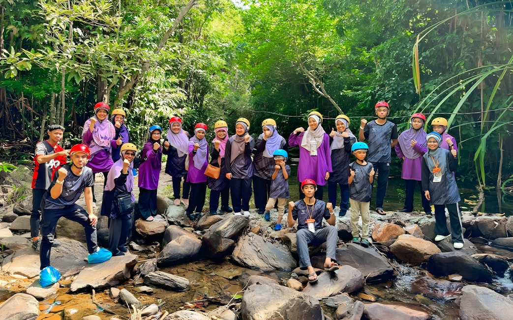 Group of people in helmets posing on rocks during Langkawi Sky ATV Ride at Mountain Manchinchang.