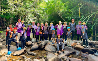 Group of people in helmets posing on rocks during Langkawi Sky ATV Ride at Mountain Manchinchang.