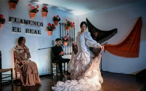 Flamenco dancer performing at El Real in Seville with musicians.