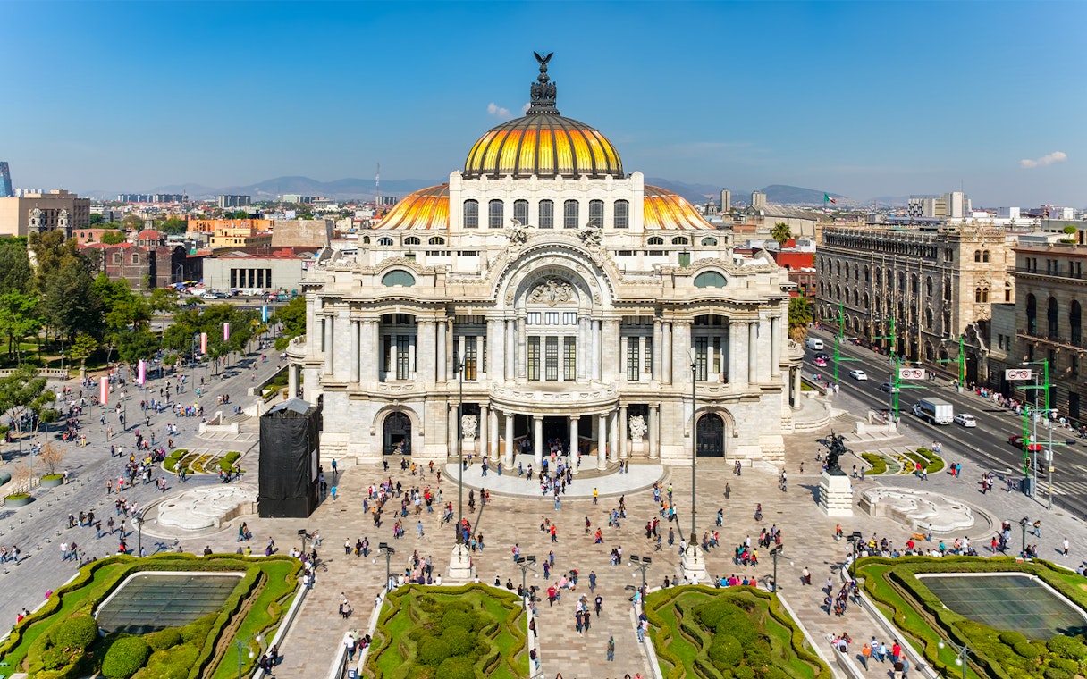 Palace of Fine Arts in Mexico City with people walking in the plaza.
