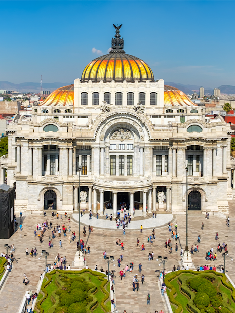 Palace of Fine Arts in Mexico City with people walking in the plaza.