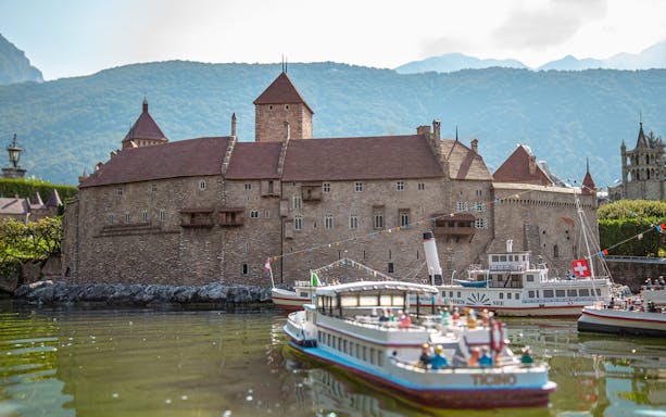 Miniature model of a Swiss castle with boats on a lake at Swissminiatur.