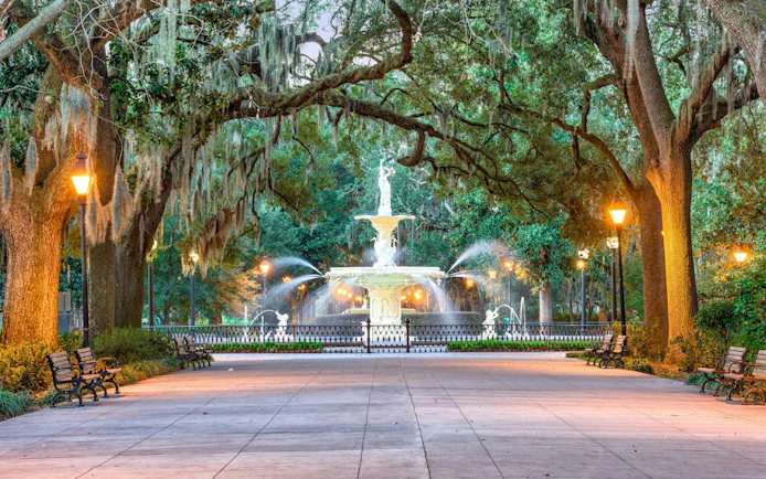Forsyth Park fountain in Savannah, Georgia, surrounded by oak trees and benches.