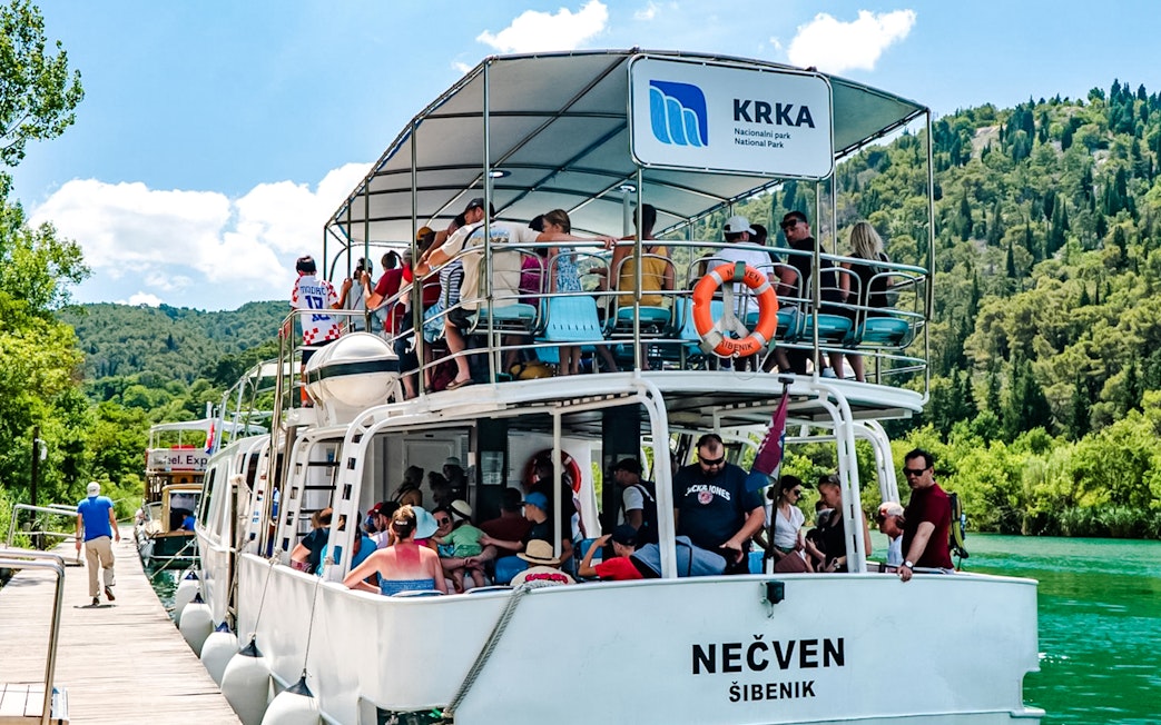 Guests enjoying boat ride at Krka National Park with lush greenery in the background.