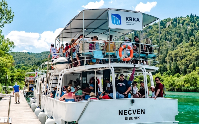 Guests enjoying boat ride at Krka National Park with lush greenery in the background.
