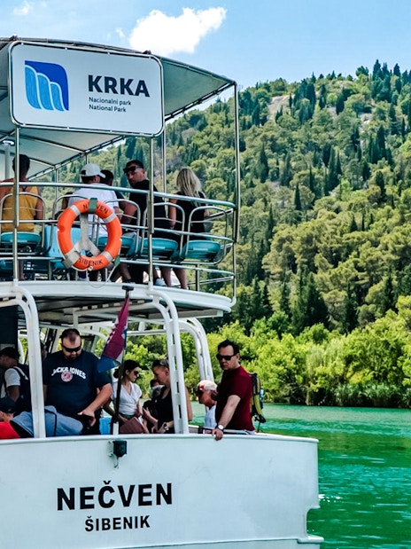 Guests enjoying boat ride at Krka National Park with lush greenery in the background.