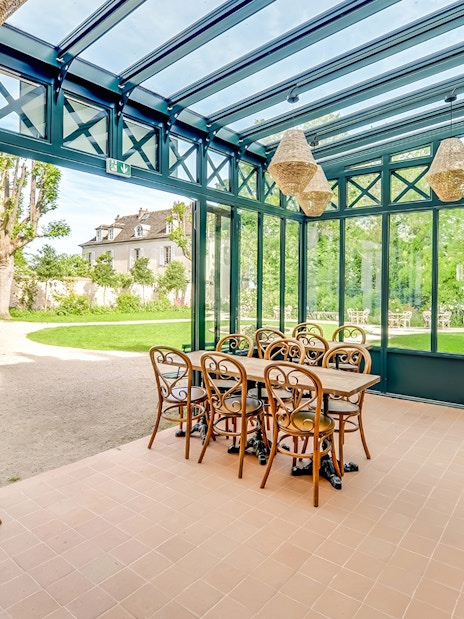 Conservatory seating area at Montmartre Museum, Paris, with garden view.