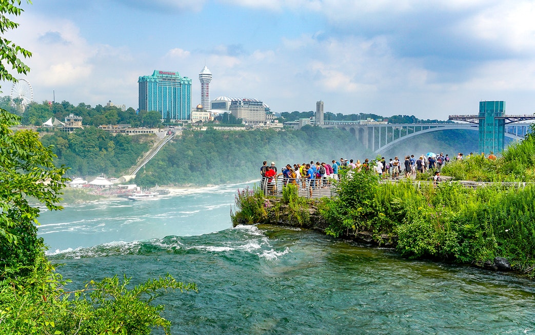 Tourists on Luna Island viewing Niagara Gorge through mist at Niagara Falls.