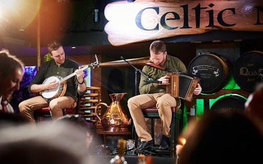 Musicians playing banjo and accordion at Dublin Celtic Nights show.