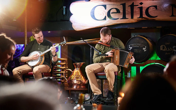 Musicians playing banjo and accordion at Dublin Celtic Nights show.