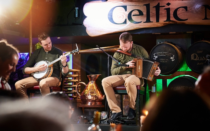 Musicians playing banjo and accordion at Dublin Celtic Nights show.