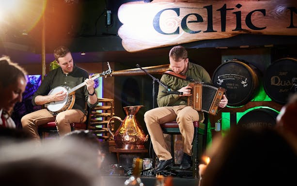Musicians playing banjo and accordion at Dublin Celtic Nights show.