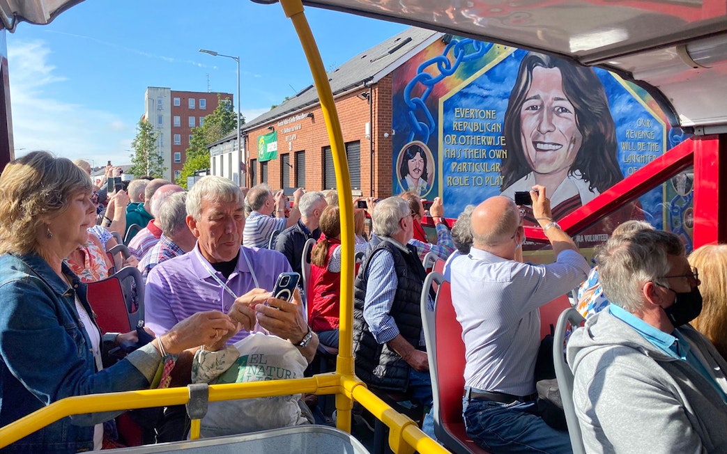 Tourists on a bus tour viewing the Bobby Sands mural on Falls Road, Belfast.