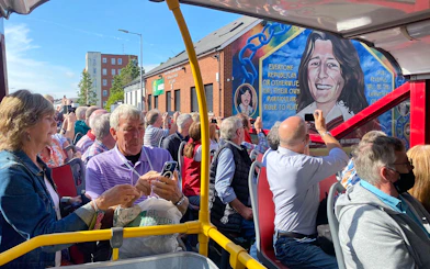 Tourists on a bus tour viewing the Bobby Sands mural on Falls Road, Belfast.