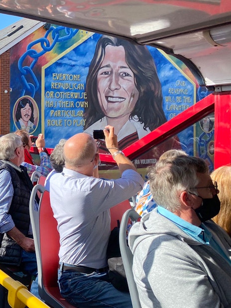 Tourists on a bus tour viewing the Bobby Sands mural on Falls Road, Belfast.