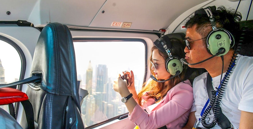 Couple enjoying aerial view of Dubai from helicopter.