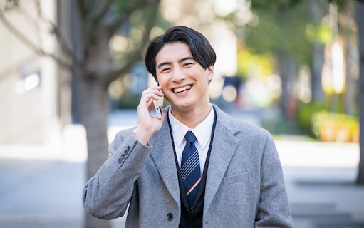 Man in a suit talking on a phone in a Japanese city street.