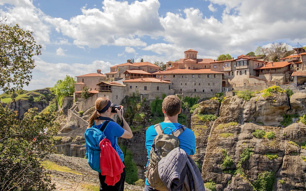 Guests hiking near Meteora monastery, Greece, capturing scenic views.