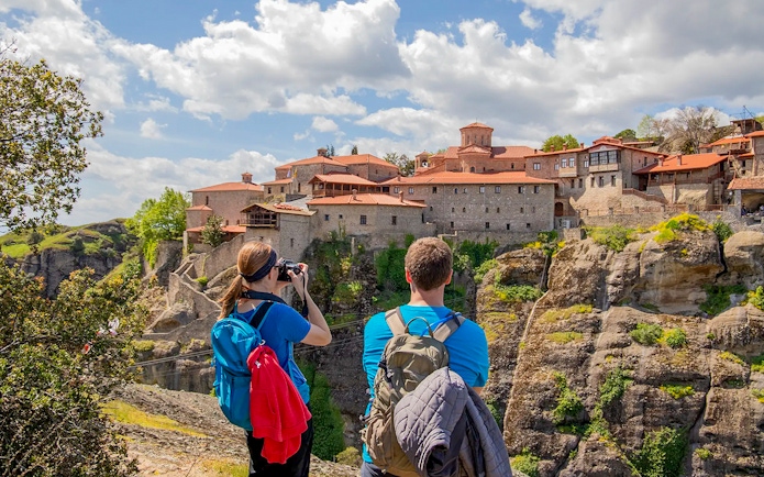 Guests hiking near Meteora monastery, Greece, capturing scenic views.