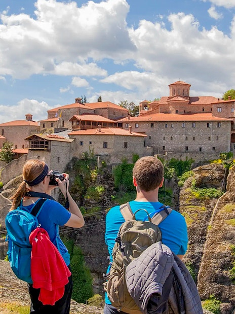 Guests hiking near Meteora monastery, Greece, capturing scenic views.