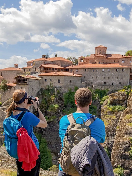 Guests hiking near Meteora monastery, Greece, capturing scenic views.