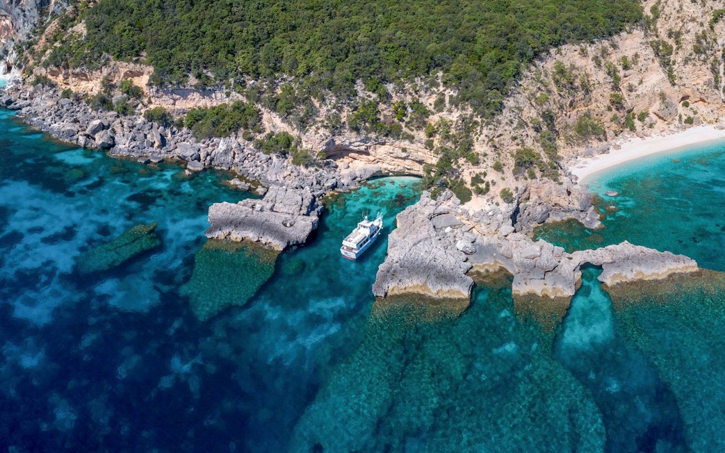 Aerial view of a boat near rocky coastline at Gulf of Orosei, Italy.