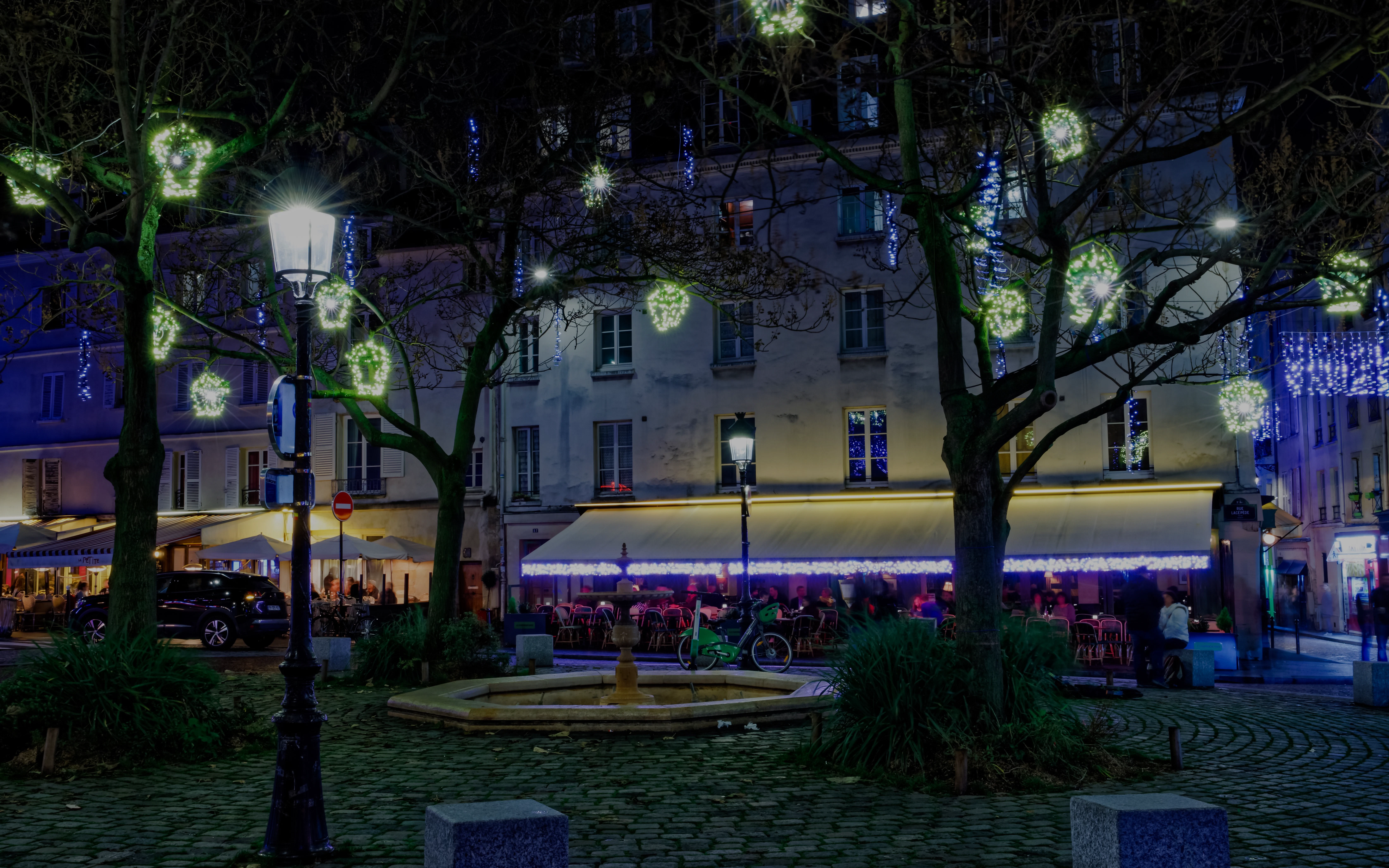 Place de la Contrescarpe at night with illuminated trees and outdoor café.