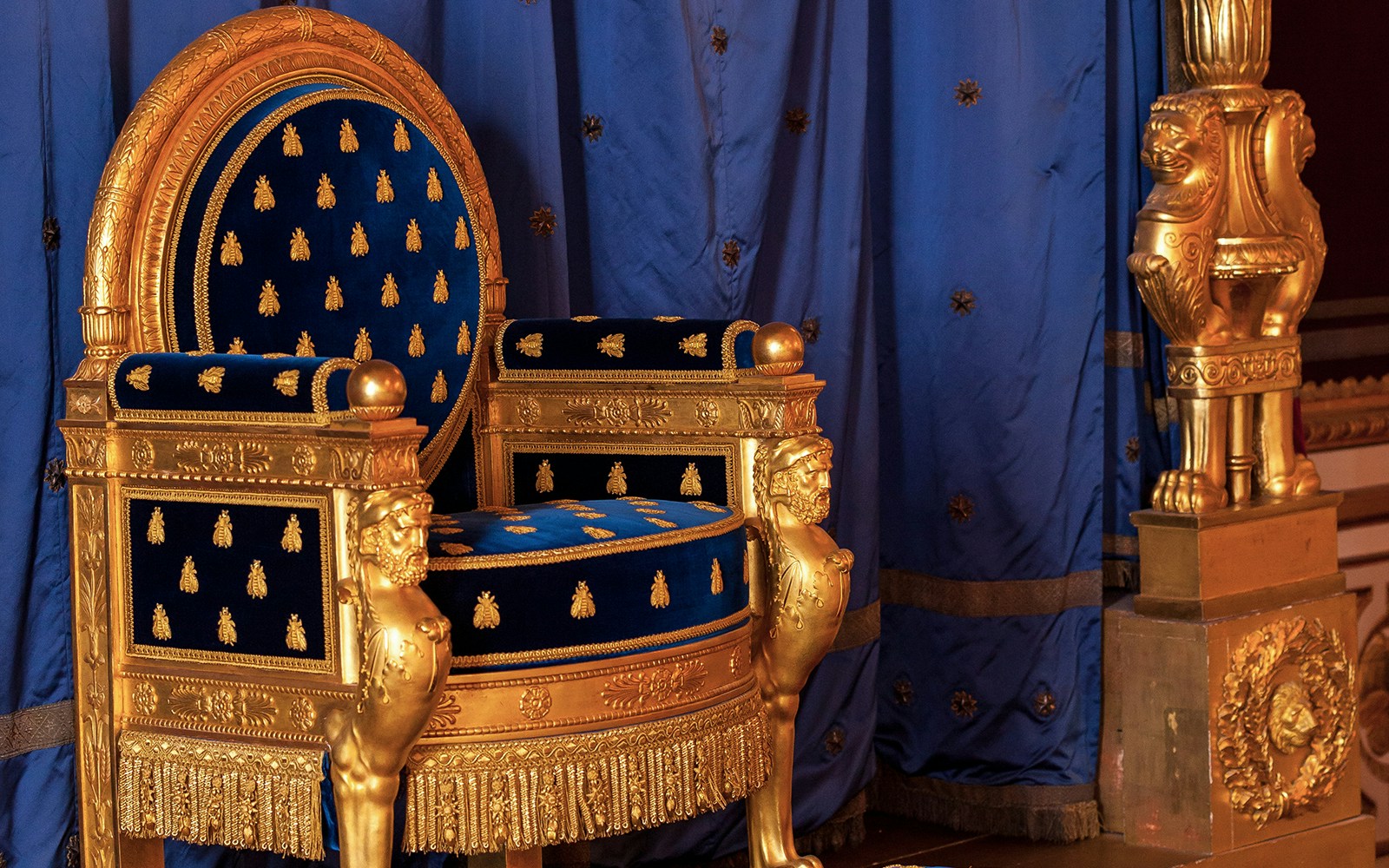 Napoleon's throne at Chateau de Fontainebleau, featuring gold detailing and blue upholstery.