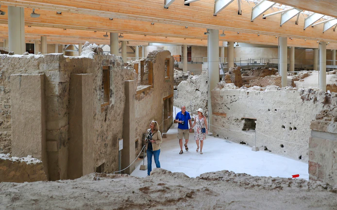 Visitors exploring ancient ruins at the Akrotiri Archaeological Site, Greece.