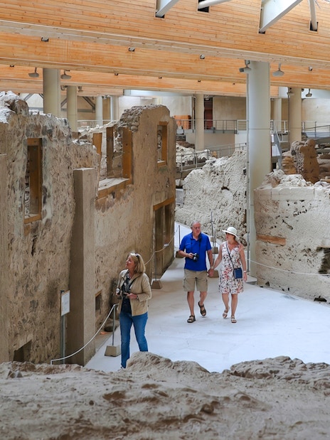 Visitors exploring ancient ruins at the Akrotiri Archaeological Site, Greece.
