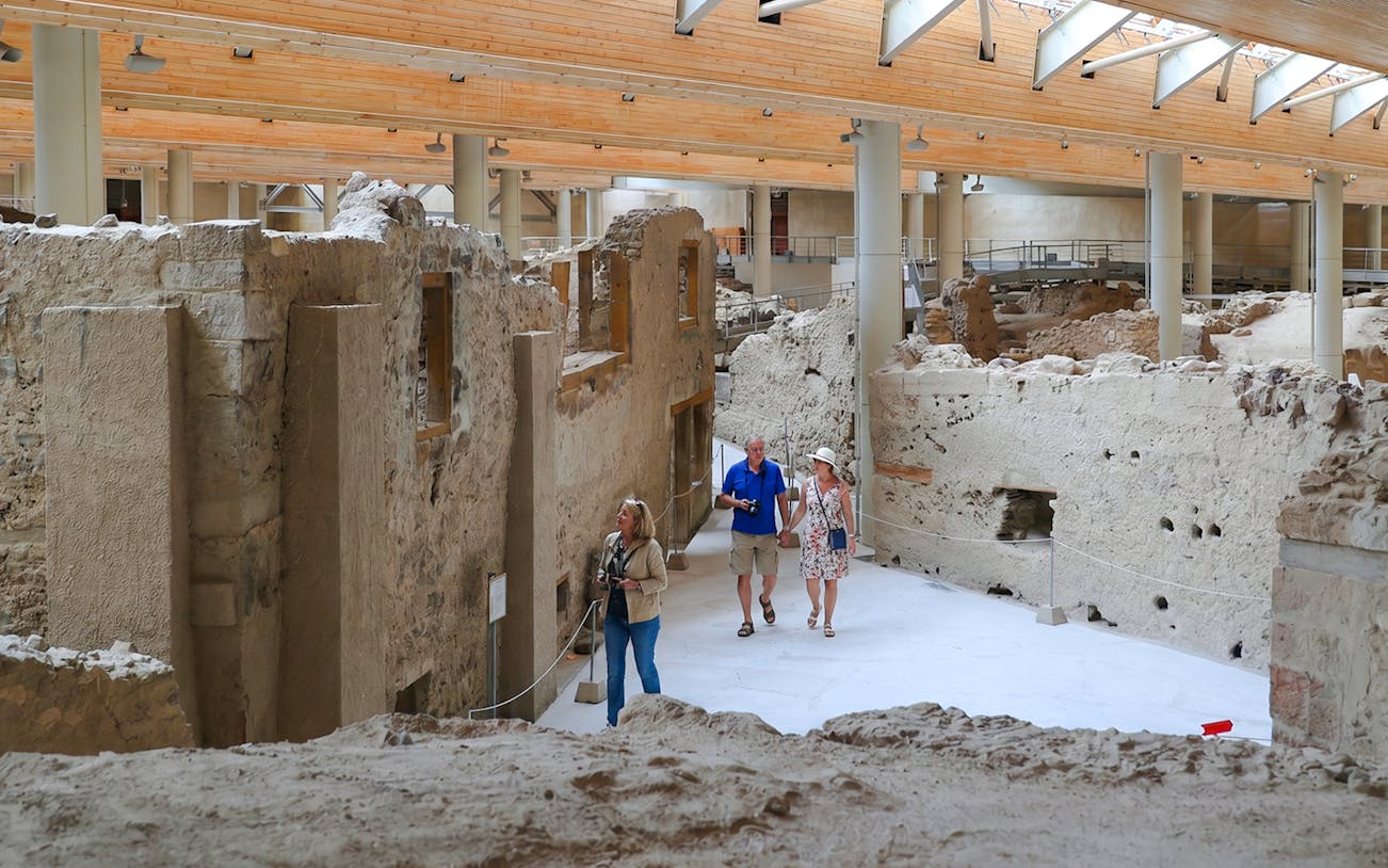 Visitors exploring ancient ruins at the Akrotiri Archaeological Site, Greece.