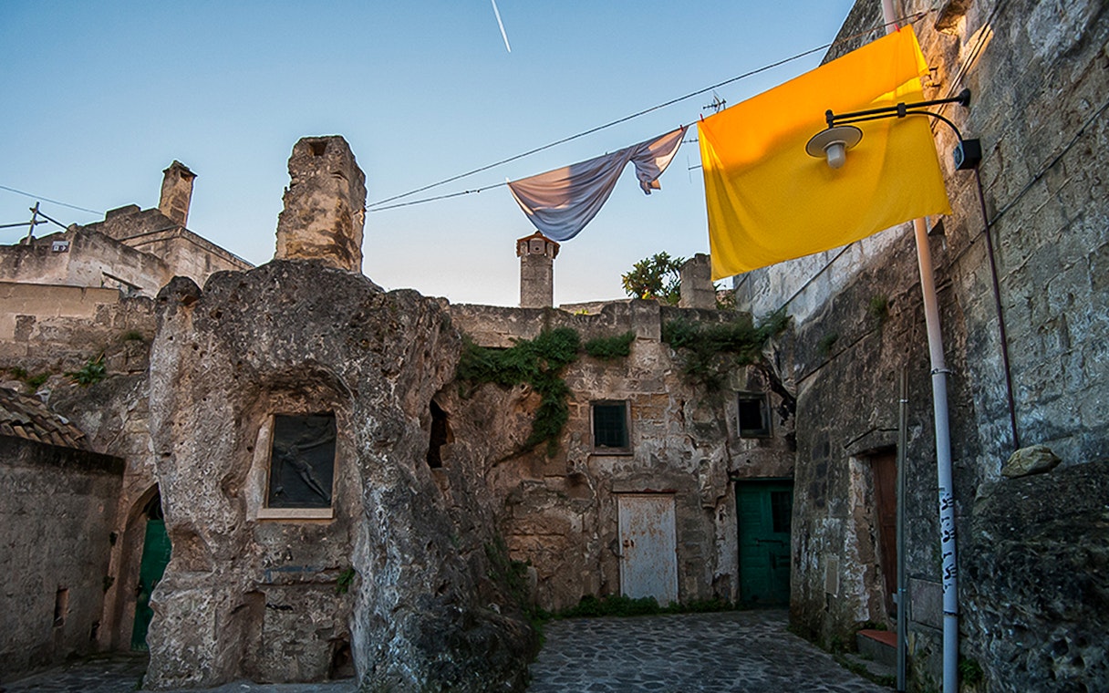 Ancient stone buildings in Sassi of Matera with laundry hanging above.