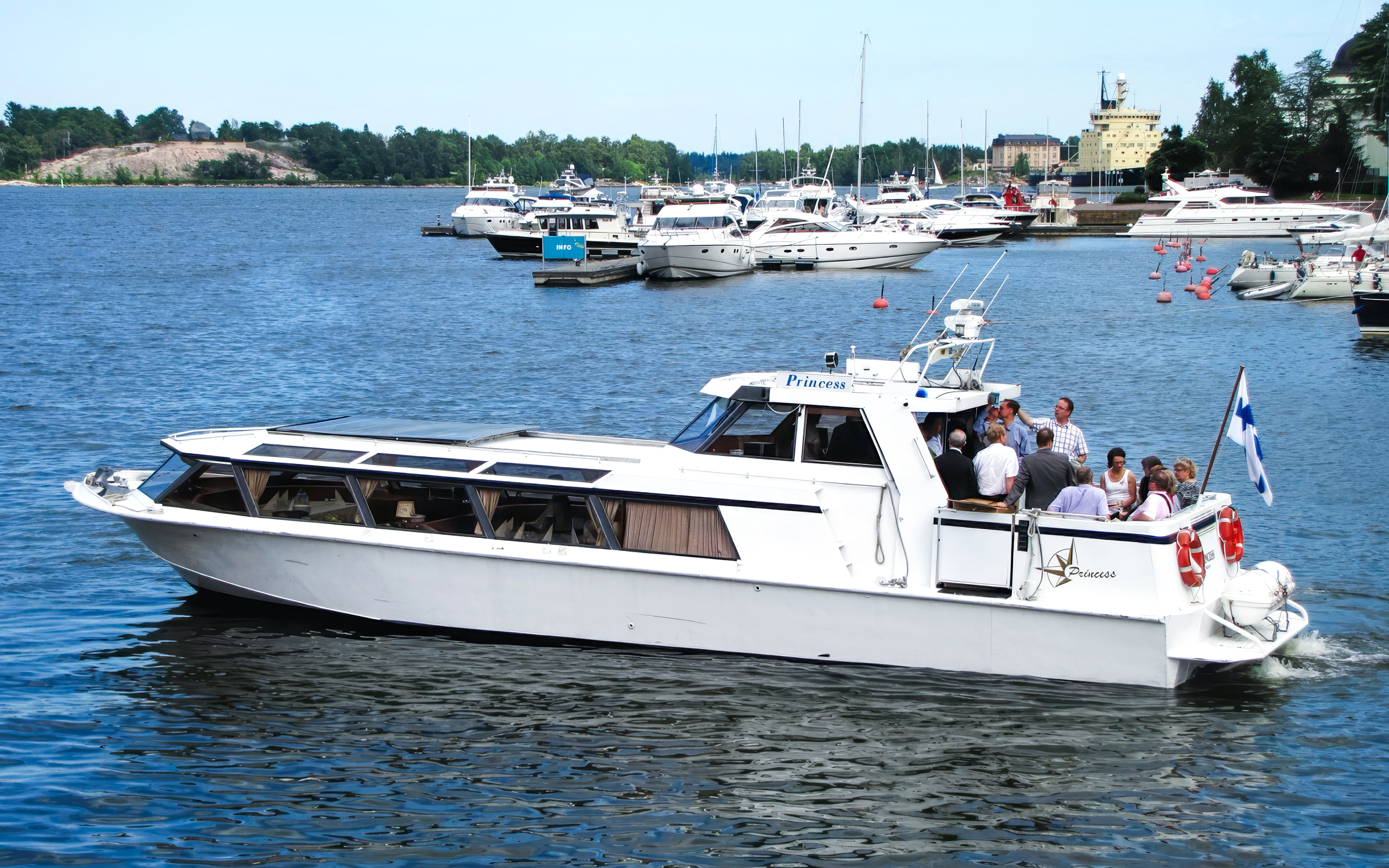 Private boat cruise in Helsinki harbor with passengers enjoying skyline views.