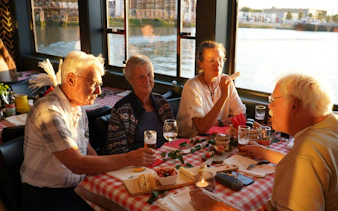 Group enjoying pizza and drinks on a river cruise at sunset.