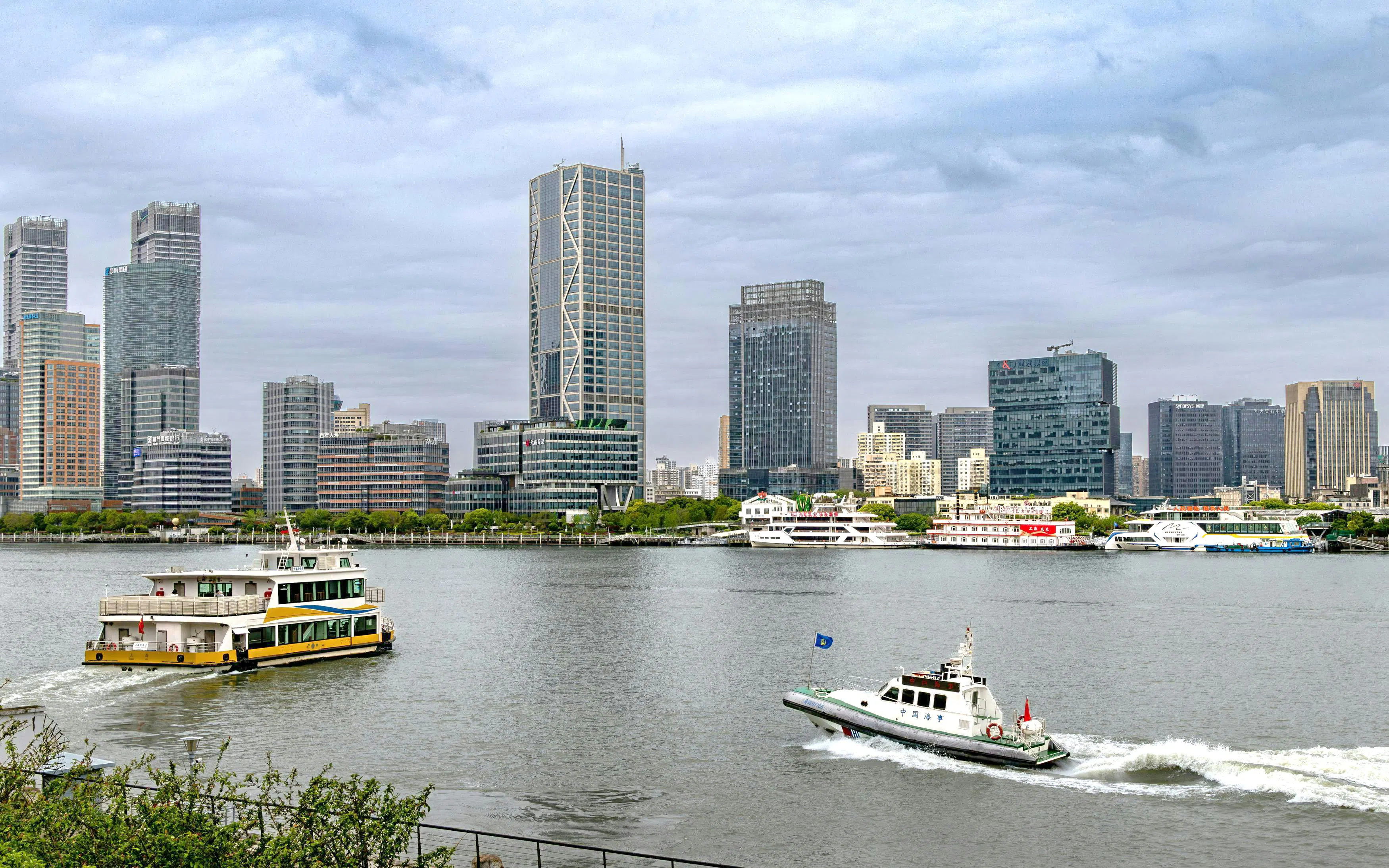Cruise boats on Huangpu River with Shanghai skyline in the background.