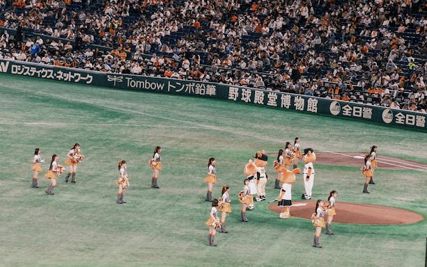 Cheerleaders and mascots on a baseball field during a game in Japan.