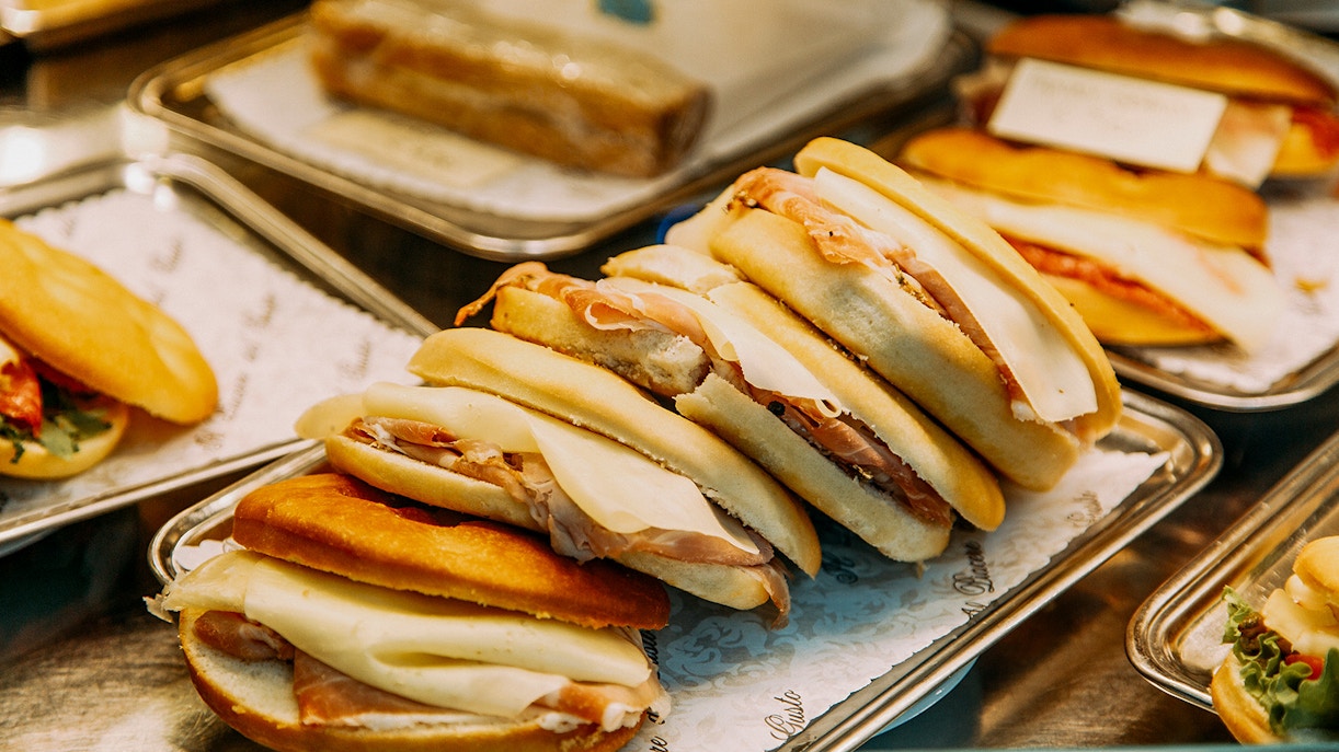 Sandwiches with cured meats and cheese on display in a Roman deli.
