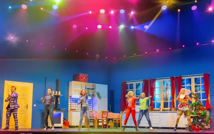 Performers on stage during Bibi & Tina musical in Berlin, colorful lights above.
