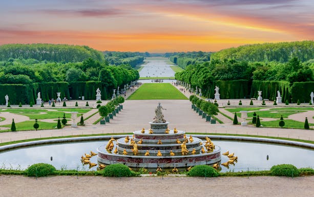 Fountain and gardens at Versailles Palace during sunset, France.