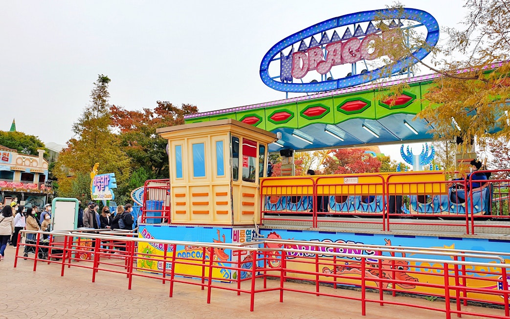 Gyeongju World amusement park ride with colorful signage and waiting visitors.