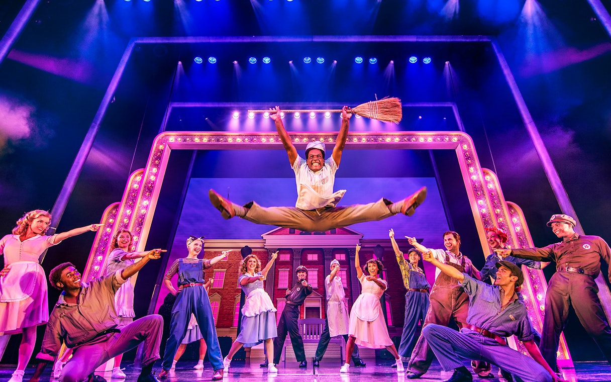 Performers in a dynamic dance scene from a "Back to the Future" stage show.
