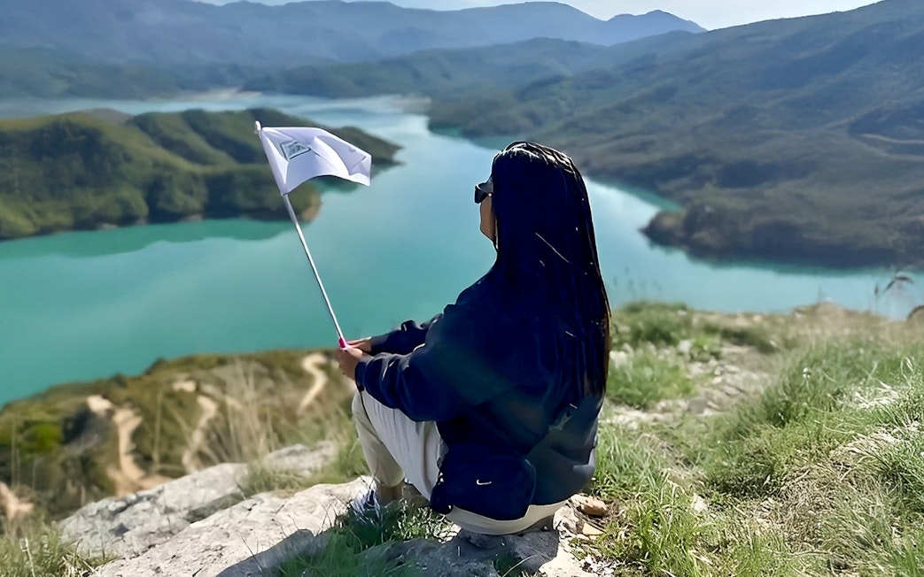 Guest overlooking Bovilla Lake with flag during 4x4 offroad tour from Tirana.