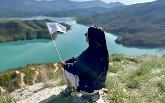 Guest overlooking Bovilla Lake with flag during 4x4 offroad tour from Tirana.