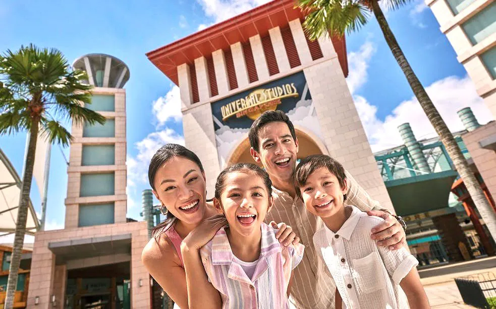 Family smiling in front of Universal Studios Singapore entrance.