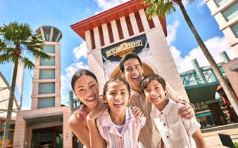 Family smiling in front of Universal Studios Singapore entrance.