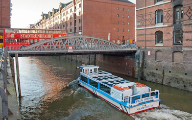 Hop-on hop-off bus and river cruise boat in Hamburg's Speicherstadt district.