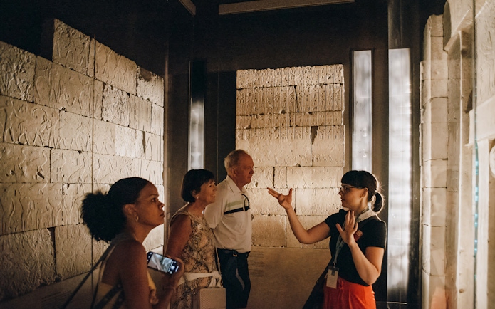 Tour guide and visitors discuss ancient Egyptian reliefs at the Metropolitan Museum of Art.