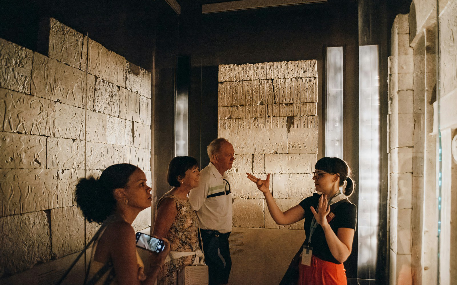 Tour guide and visitors discuss ancient Egyptian reliefs at the Metropolitan Museum of Art.