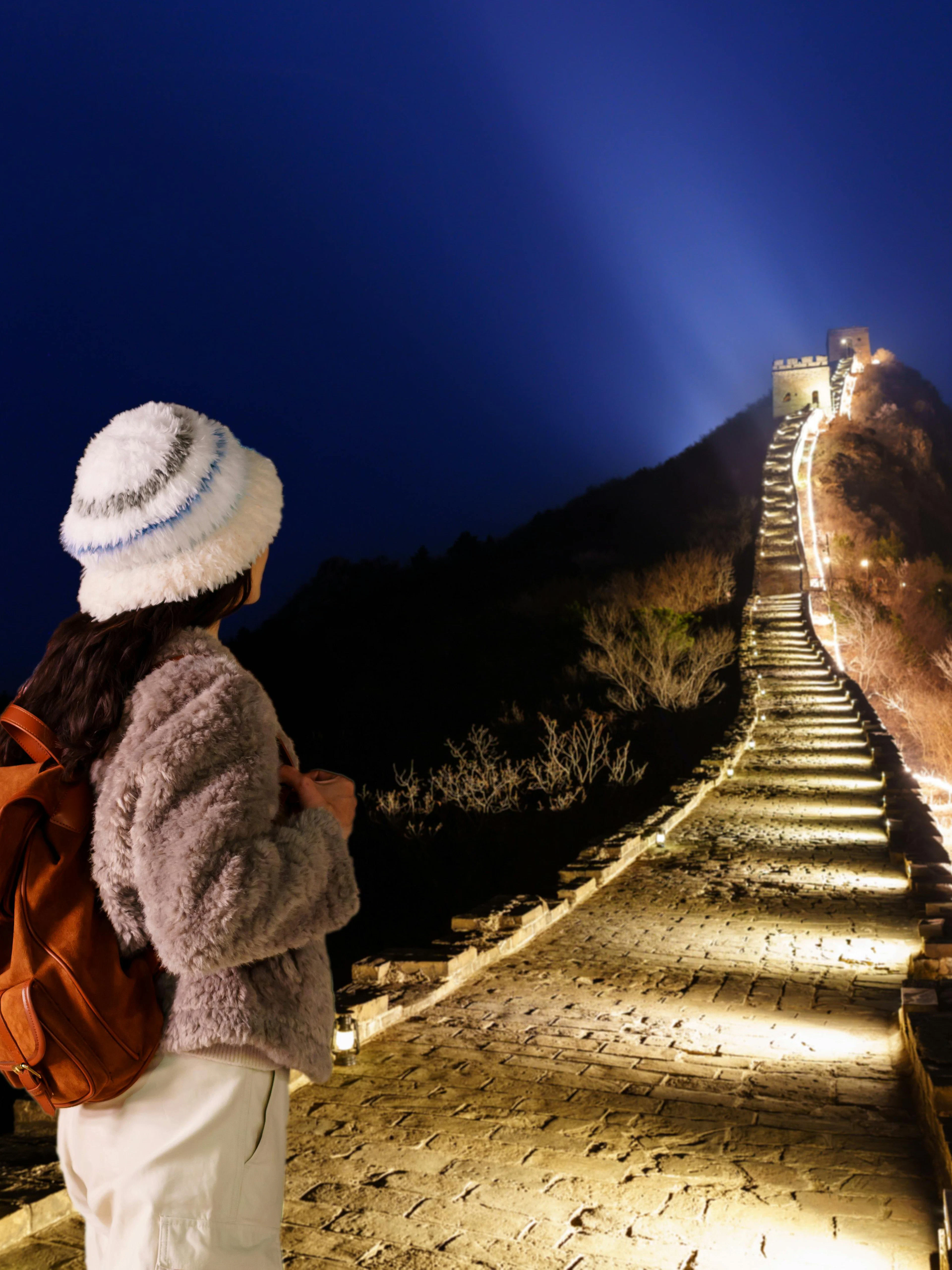 Traveler viewing illuminated Badaling Great Wall at night, Beijing.