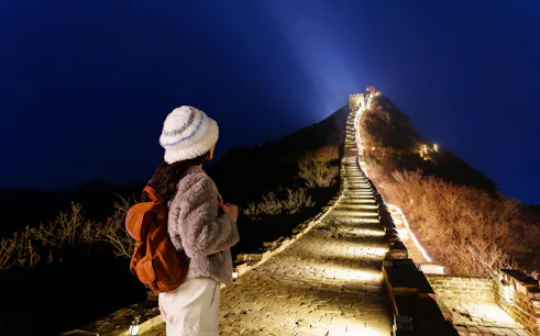 Traveler viewing illuminated Badaling Great Wall at night, Beijing.